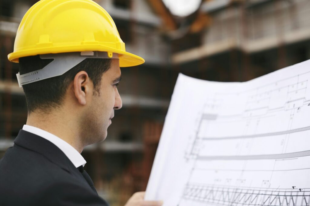 Architect In Construction Site Looking At Building Plans