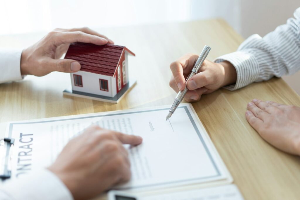 Insurance concept the realtor pointing out the place to sign the customer’s name on the paper.